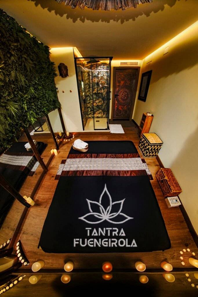 Candlelit massage bed and carved teak door in the Bali room at Tantra Fuengirola Tantric Massages
