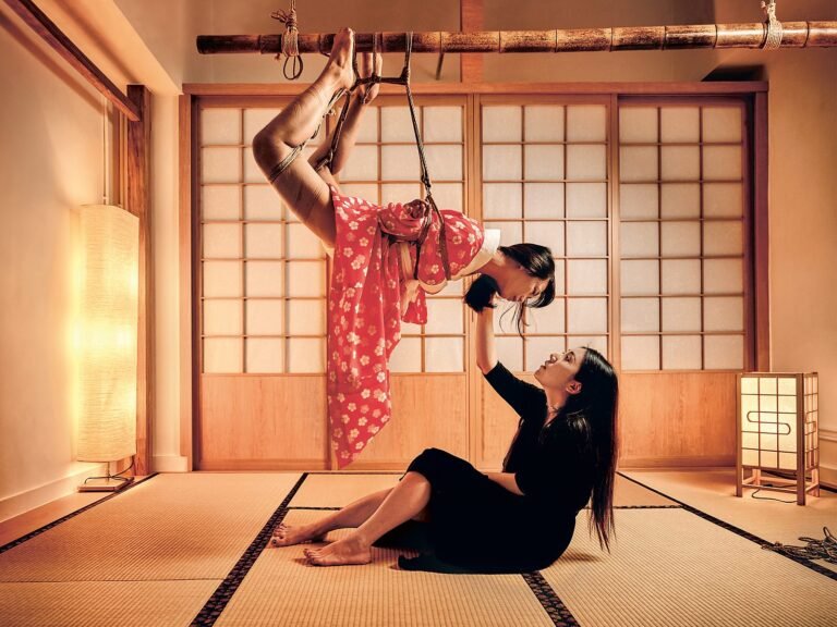 Shibari suspension in a Japanese tatami room, rope artist guiding a model in a red kimono at Tantra Fuengirola